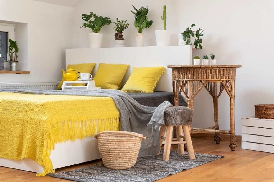 double bed with yellow pillows , bedspread and green plants